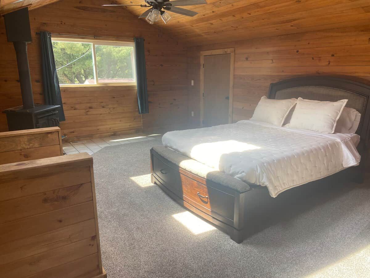 Une chambre à coucher avec un lit, une commode, une fenêtre et un ventilateur de plafond.