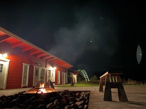 Un edificio rojo con un brasero al frente, una terraza de madera y una escalera que lleva a un segundo nivel.