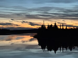 Un lago tranquilo que refleja el cielo, con árboles en la orilla.