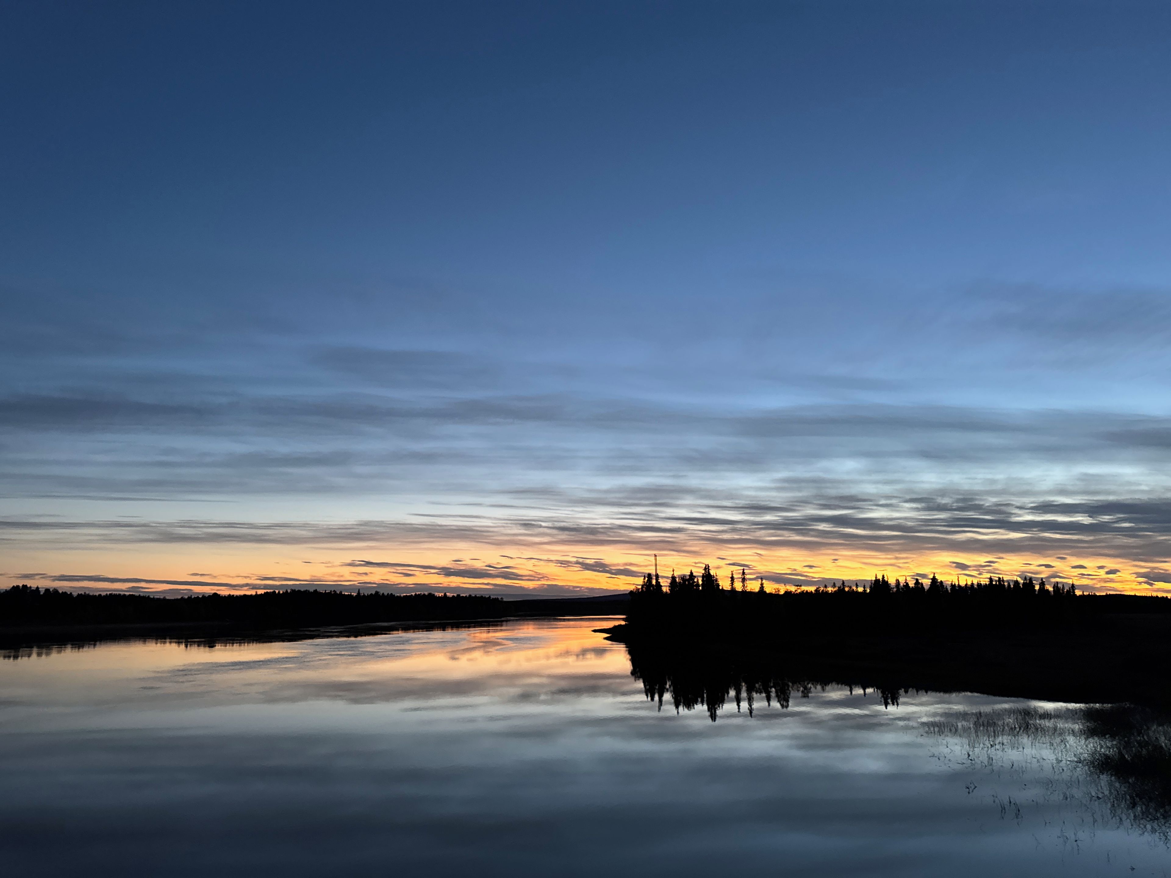 Ein ruhiger See spiegelt den Himmel während des Sonnenuntergangs.