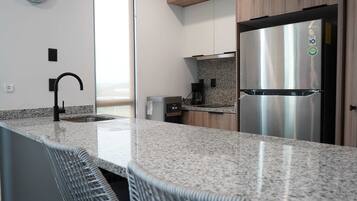 A modern kitchen with granite countertops, a stainless steel refrigerator, and a built-in dishwasher.