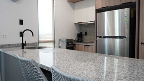A modern kitchen with granite countertops, a stainless steel refrigerator, and a built-in dishwasher.