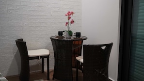 A small, dark wicker table with two chairs, a vase with pink flowers, and two black mugs. - Torre W Beachfront Condo: Ocean View & Pools (Mazatlán)