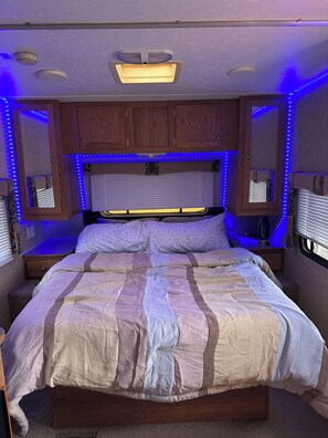 A bedroom with a bed, wooden cabinets, a mirror, and LED lighting. - Renegade Ranch and Hunt Club – Site 5 (St George)