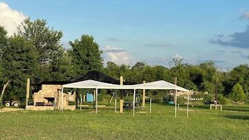 A campsite with a brick structure, a white tent, and a picnic table.
