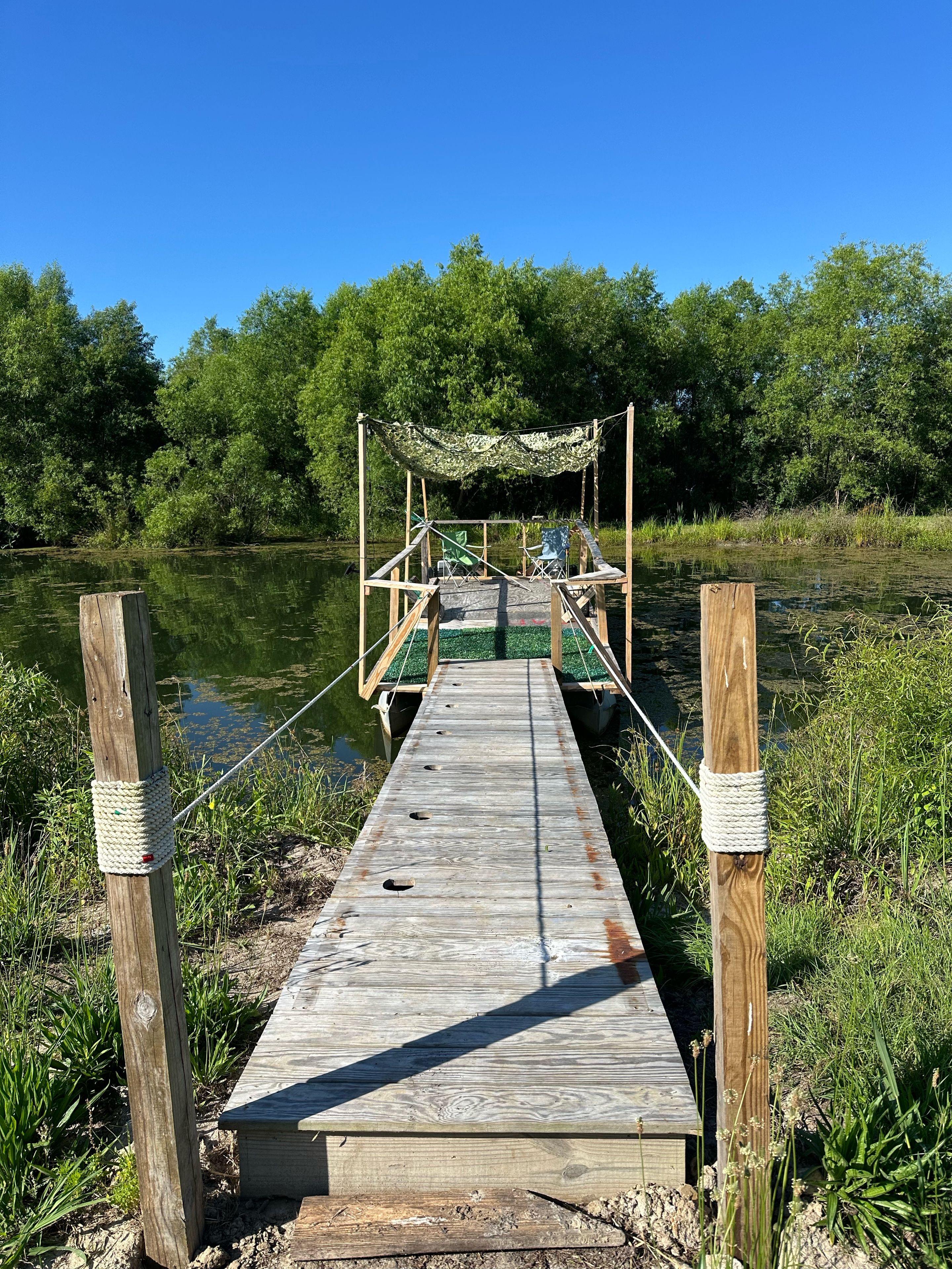 Un muelle de madera que se adentra en el agua, con una pérgola y zona de estar al final.