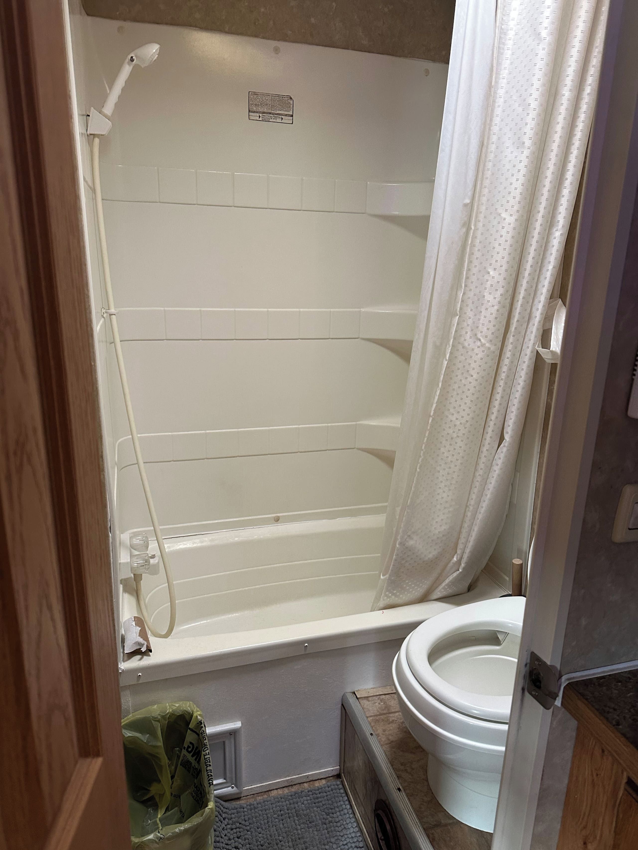 A small bathroom with a white bathtub, a toilet, and a showerhead.