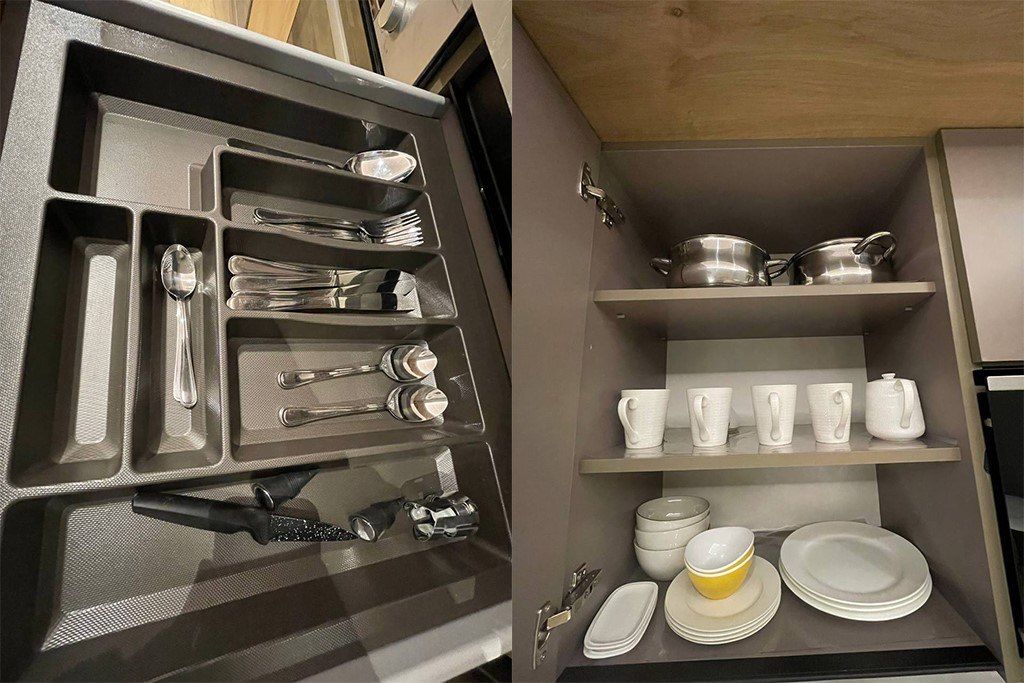 Cocina compacta con almacenamiento integrado para utensilios y batería de cocina, y un estante con vajilla y vasos.