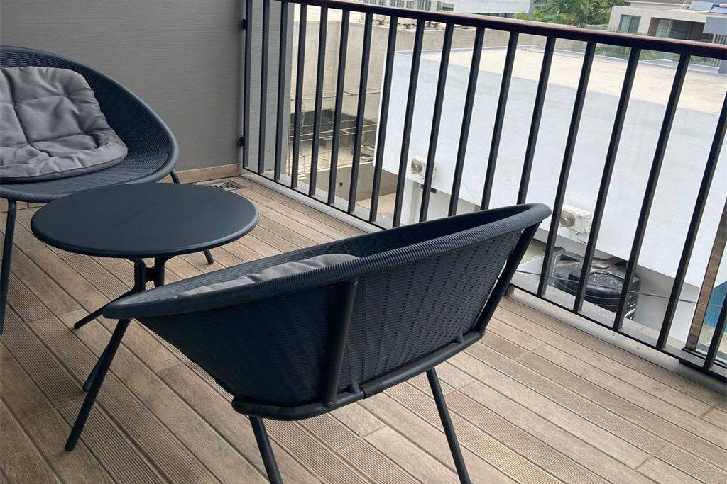 Un balcon avec une chaise et une petite table, une balustrade et une vue sur la rue.