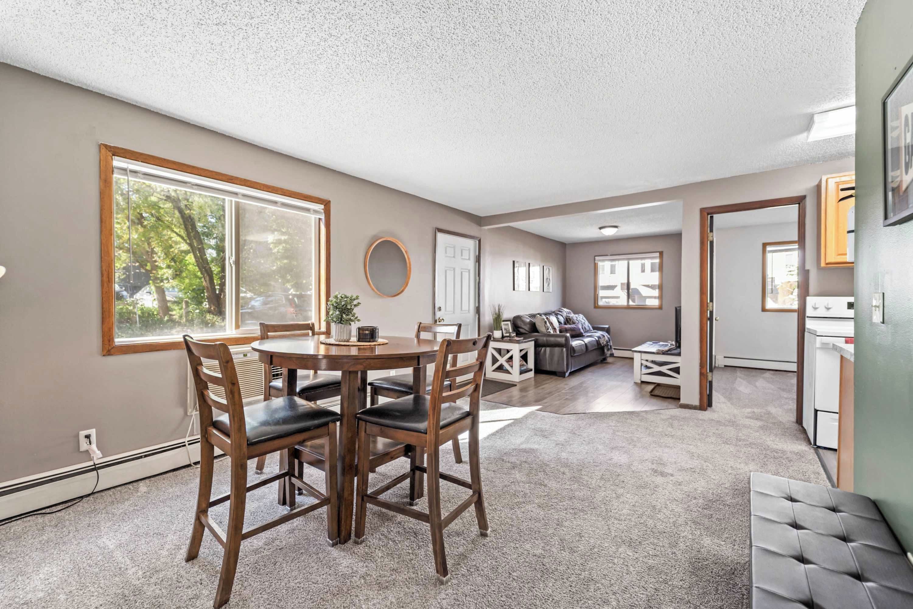 A spacious living area with a dining table, chairs, a sofa, and a kitchen area.