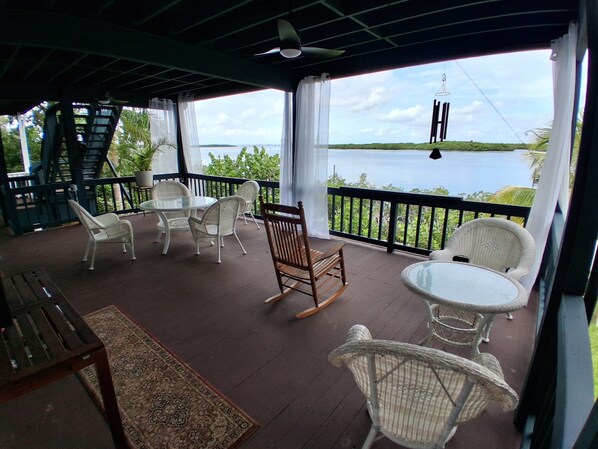 A covered outdoor seating area with wicker furniture, a glass table, and a view of a body of water. - Private Waterfront Hideaway in Punta Gorda (Punta Gorda)