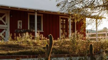 A red building with a white roof, surrounded by cacti and desert vegetation.