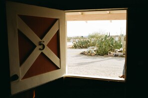 A room with a large window revealing a desert landscape with cacti and a white sculpture.