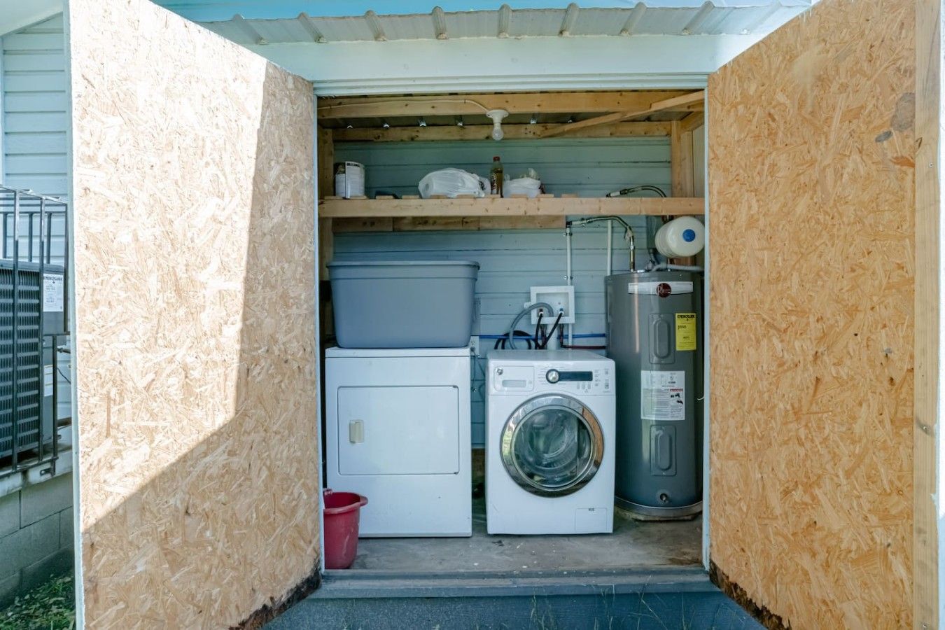 A laundry room with a washing machine, dryer, and stacked plastic bins.
