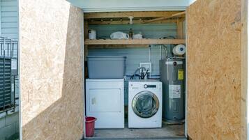 A laundry room with a washing machine, dryer, and stacked plastic bins.