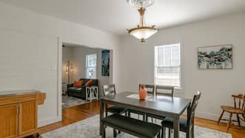 A dining area with a table, chairs, and a bench. There is a wooden cabinet and a rug on the floor.