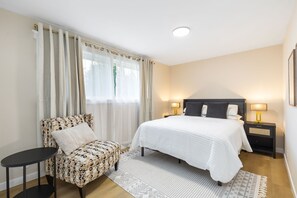 A hotel room with a bed, a chair, a bedside table, and a nightstand. - Gorgeous 3-bedroom townhome with AC in lovely center of Bellevue (Bellevue)