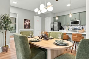 A modern kitchen with a central island, green upholstered chairs, and pendant lighting. - Designer Luxury 3BR, Stunning Lake View, Vista Cay (Orlando)