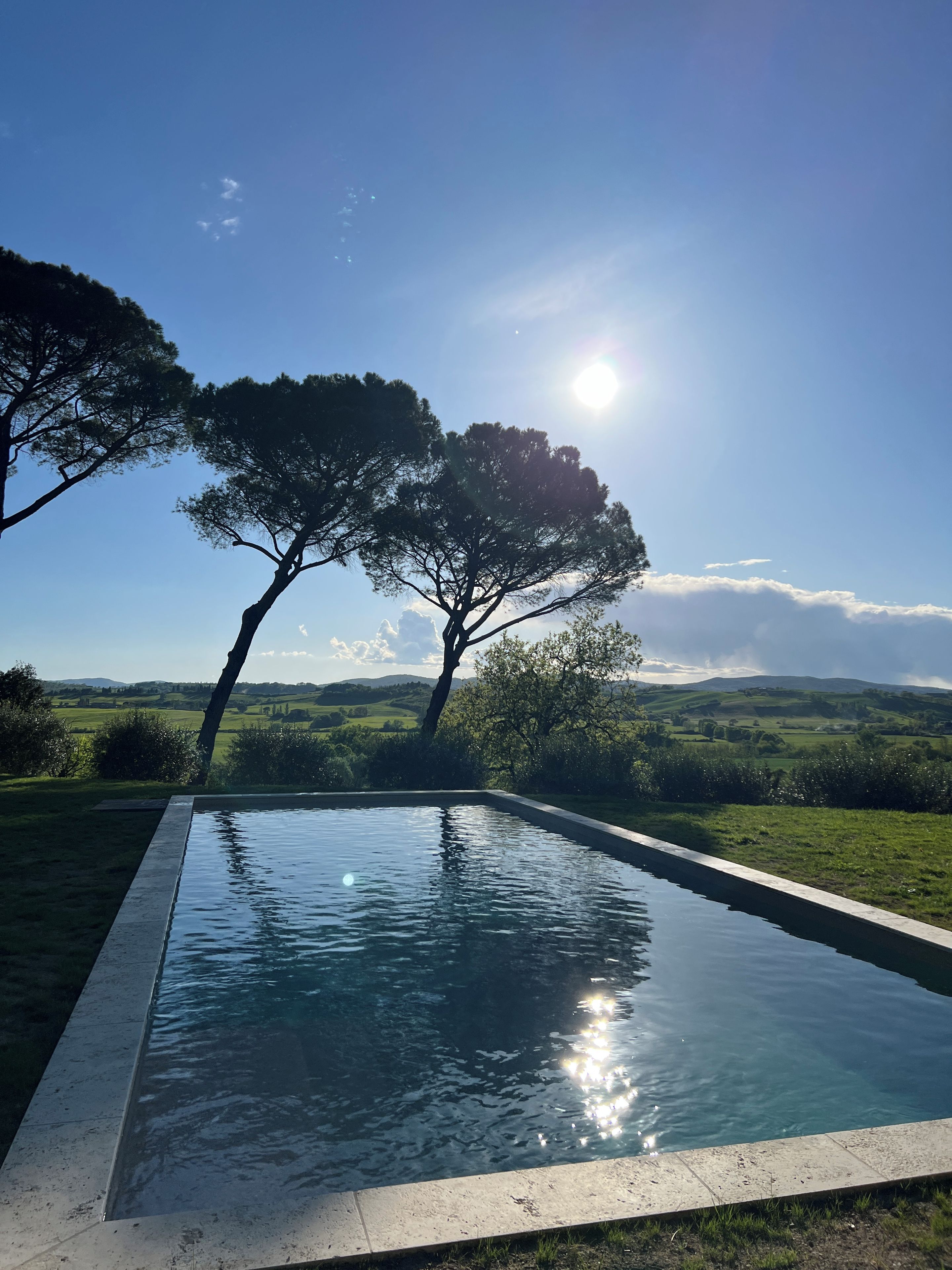 A swimming pool with a clear view of the surrounding landscape, including trees and distant hills.