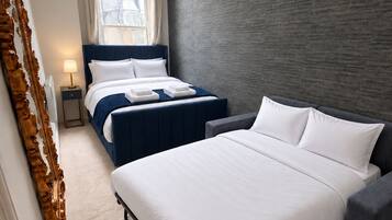 Ein modernes Hotelzimmer mit zwei Betten, einem großen Fenster und einer strukturierten grauen Wand.