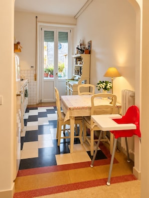 A kitchen with a checkered floor, a dining table with chairs, a red high chair, and a lamp. - Paris at the Colosseum: The style you've been looking for, in an unforgettable apartment (Roma)