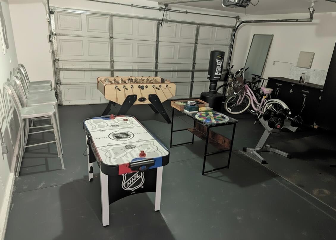 Un garaje con dos mesas de fútbol de mesa, una bicicleta y un saco de boxeo.