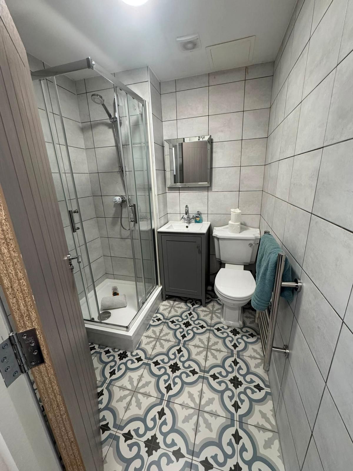 Ein Badezimmer mit Dusche, Toilette, Waschbecken und Spiegel.