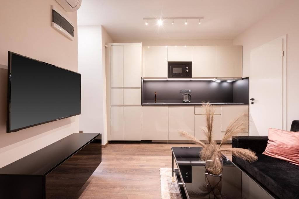 A modern kitchen with white cabinets, a black countertop, and a built-in microwave.