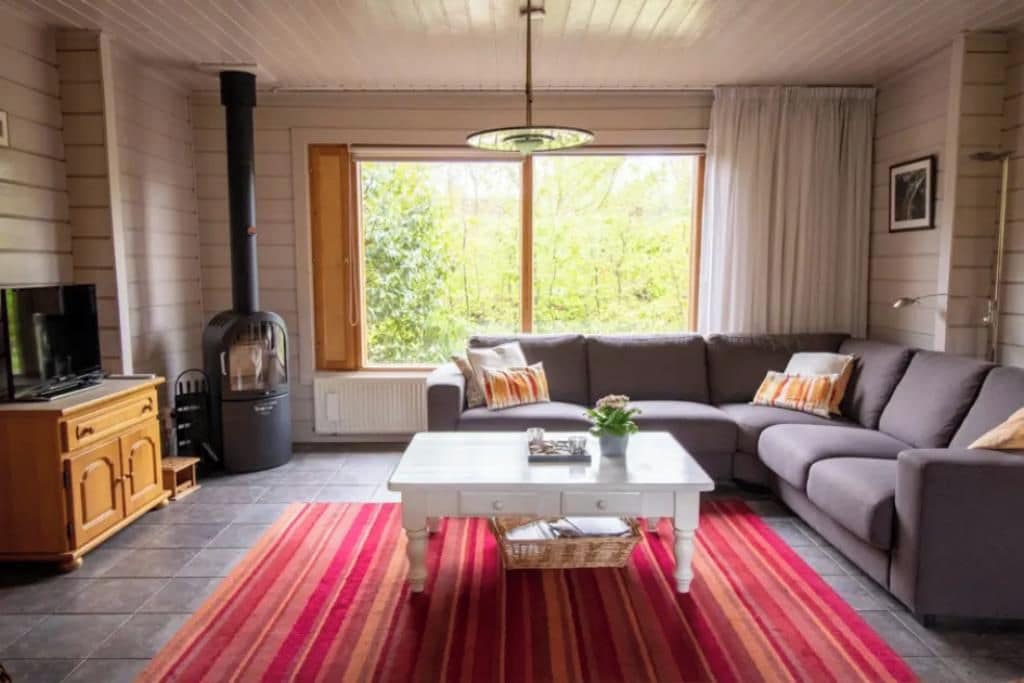 A living room with a sofa, a coffee table, a fireplace, and a window with curtains.