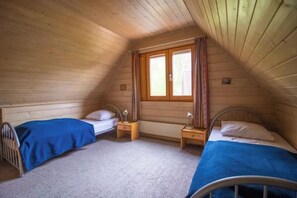 A small, sloped-roofed room with two single beds, each with a nightstand and a lamp. - Acquit 20-17 (Winterswijk)