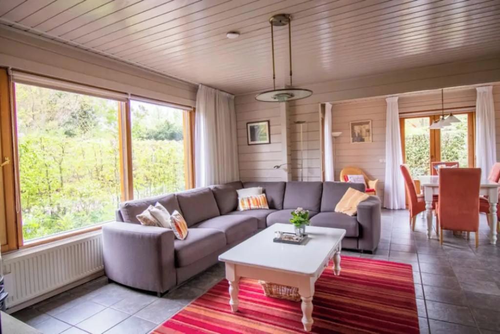 A modern living room with a sectional sofa, a coffee table, and a dining area with chairs.