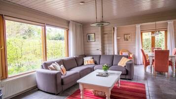 A modern living room with a sectional sofa, a coffee table, and a dining area with chairs.