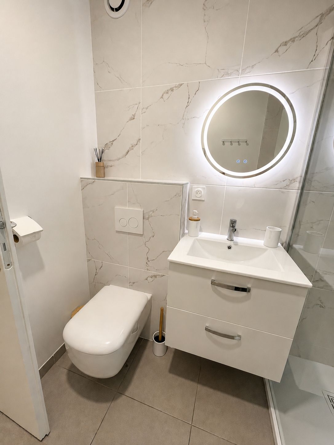 A modern bathroom with a toilet, sink, and mirror.
