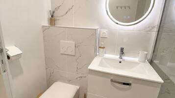 A modern bathroom with a toilet, sink, and mirror.