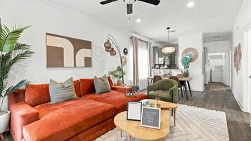 Een moderne woonkamer met een rode bank, een houten salontafel en een plafondventilator.