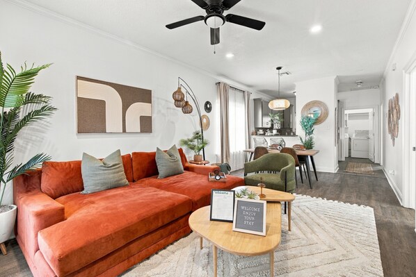 A modern living room with a red sofa, a wooden coffee table, and a ceiling fan.