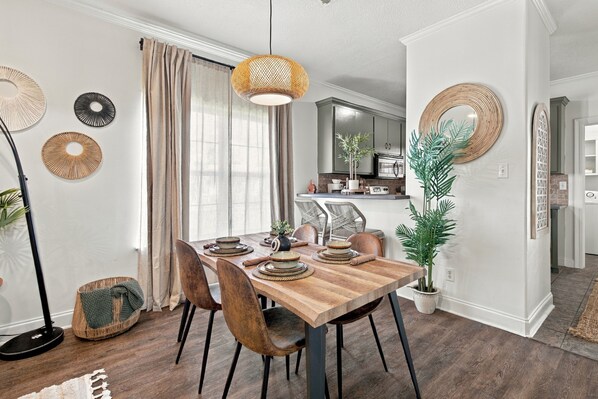 A dining area with a wooden table, chairs, and a hanging light fixture.
