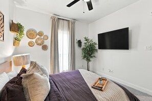 Un dormitorio moderno con una cama, un televisor montado en la pared y decoración mural.
