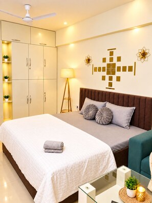 A modern bedroom with a bed, bedside table, lamp, and wardrobe.