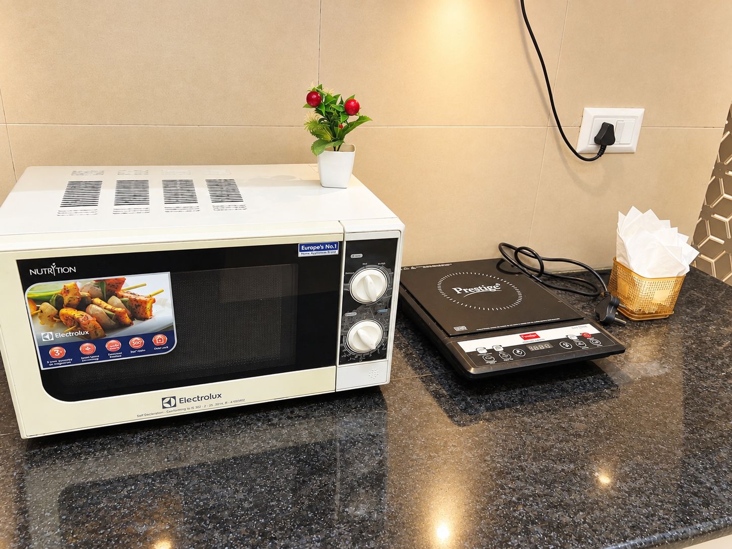 A microwave oven with a digital display, a control panel, and a power cord on a kitchen counter.