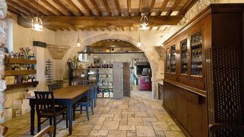 Un interno rustico con pavimento in pietra, arredi in legno e un angolo bar con bicchieri.