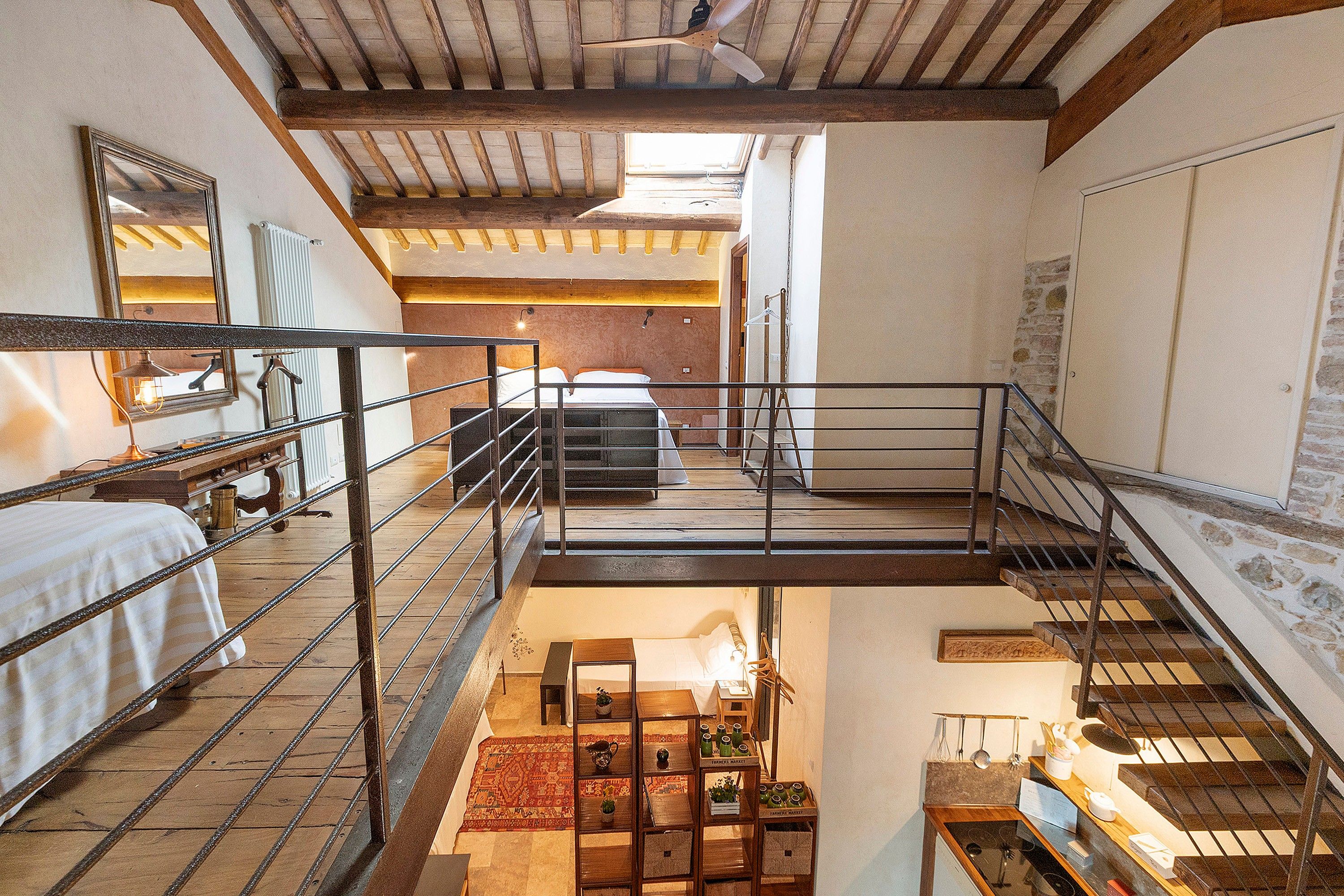 Ein mehrgeschossiges Interieur mit Treppe, Bett, Heizkörper und Spiegel.