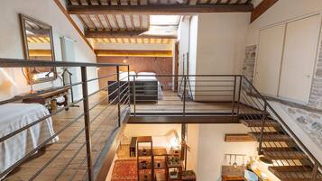 Ein mehrgeschossiges Interieur mit Treppe, Bett, Heizkörper und Spiegel.