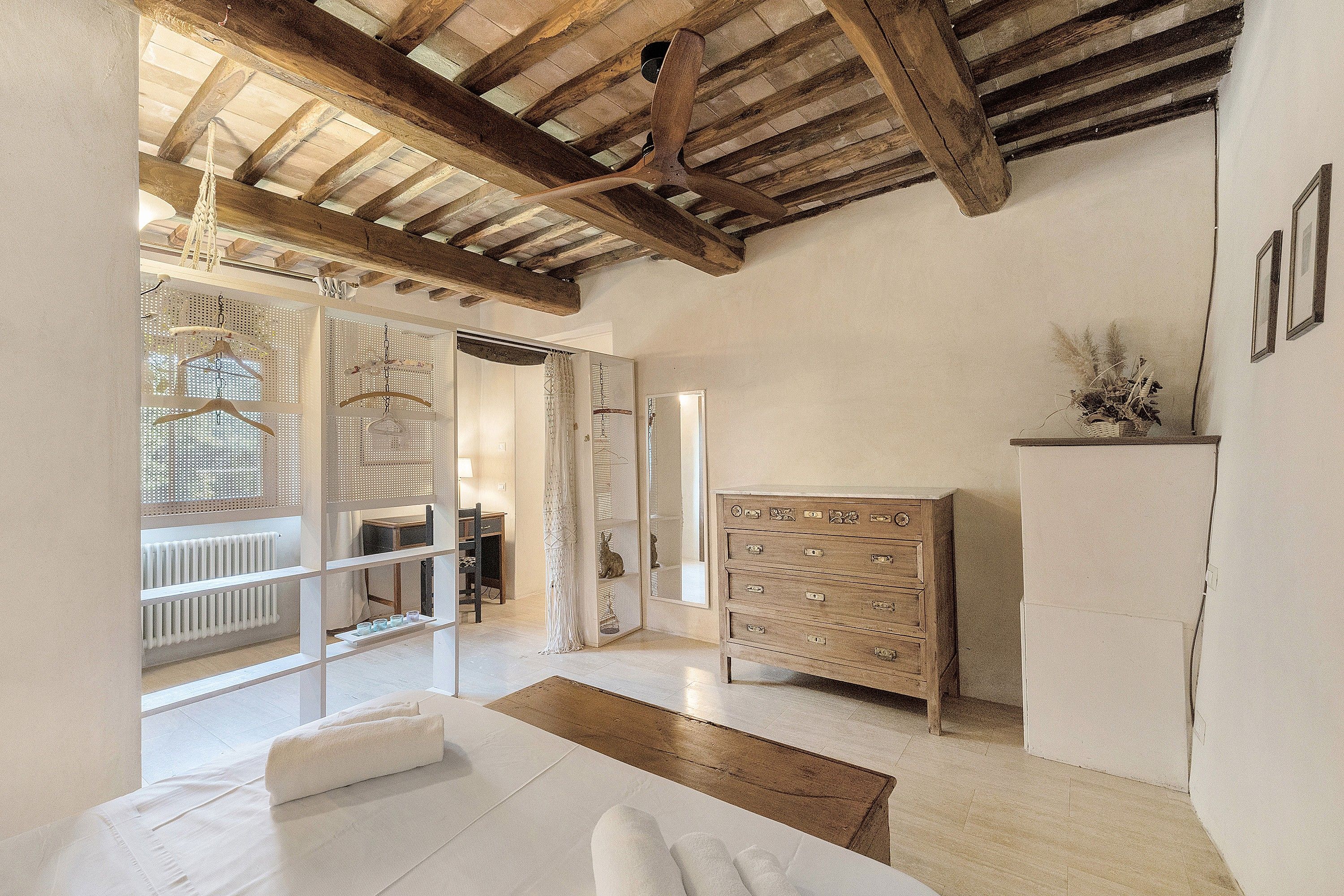 Una habitación con techo de madera, un sofá blanco, un aparador de madera y una pared con diseño.