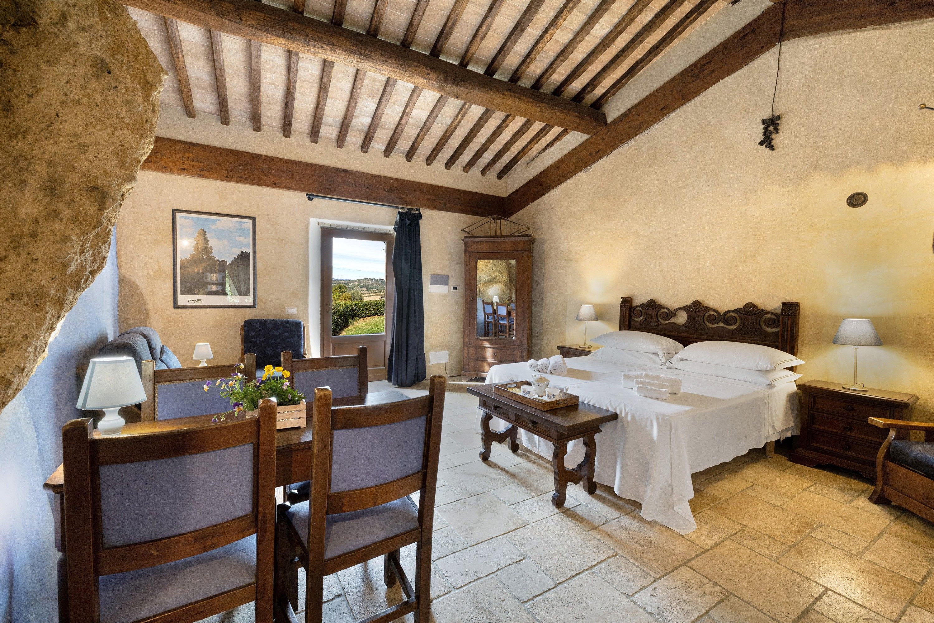 Ein gemütliches Zimmer mit Bett, Tisch mit Tablett, Stuhl und Fenster mit Blick.