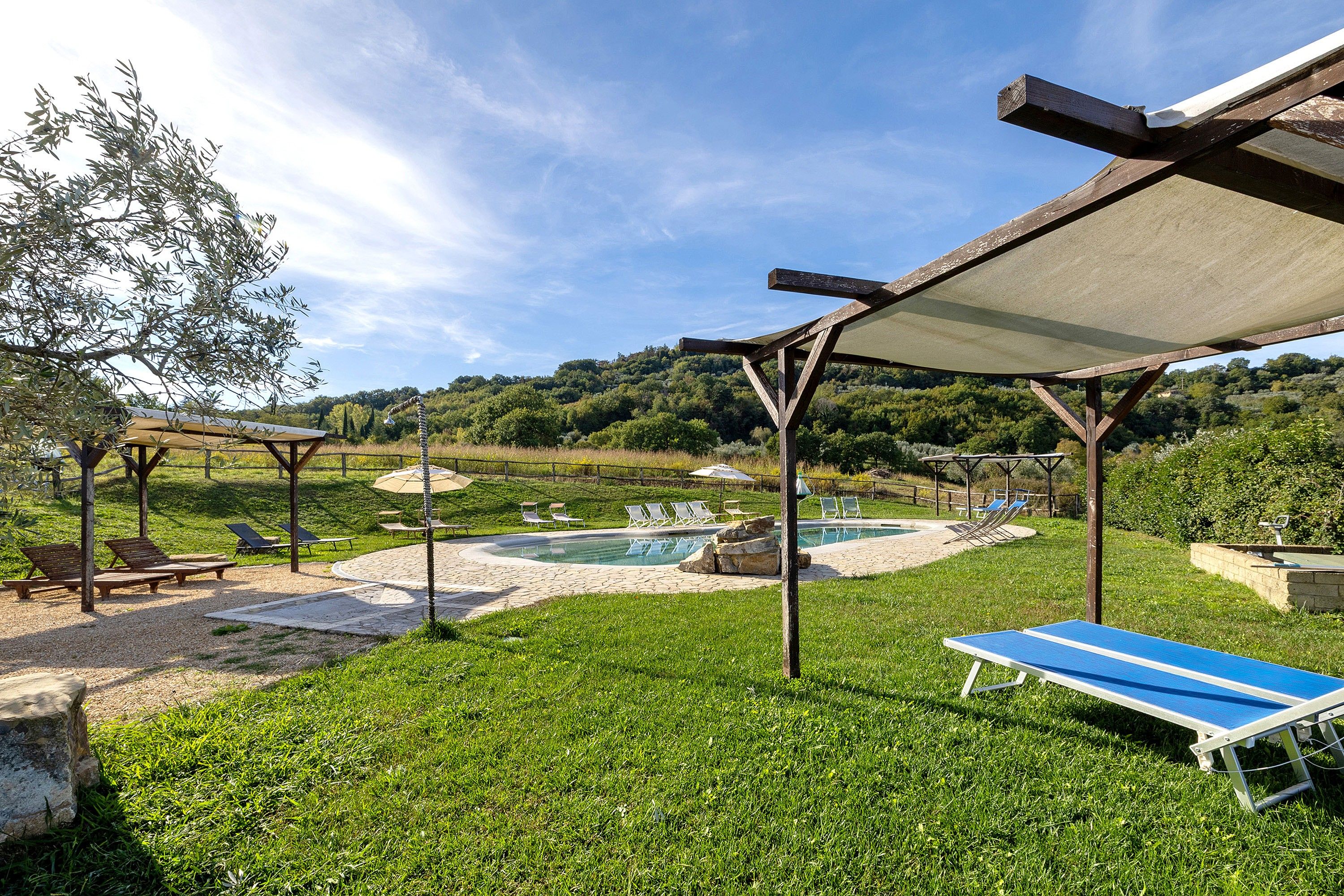 Un área de piscina con sillones de descanso y una pérgola.