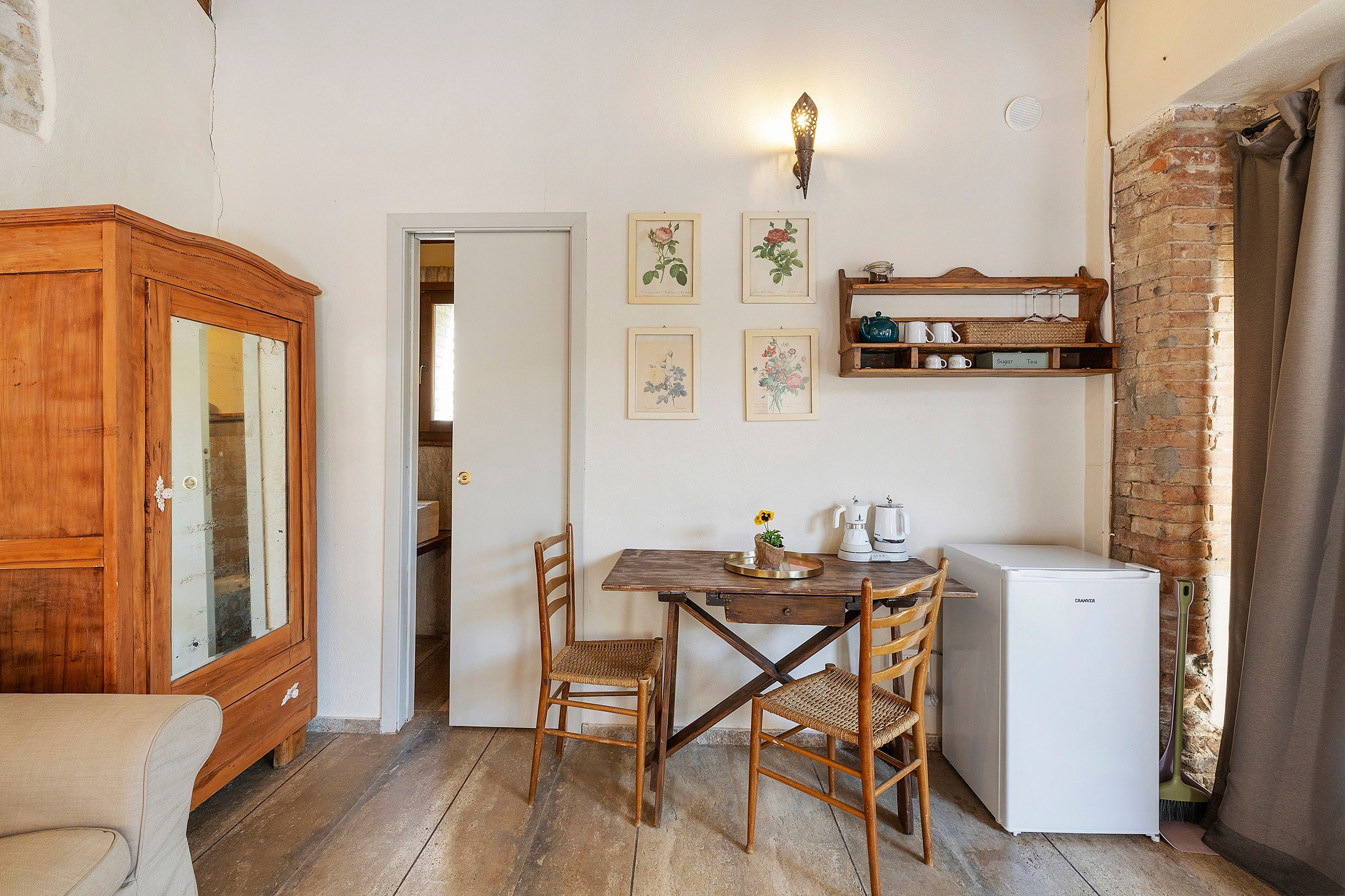 Una cocina compacta con una mesa de madera, sillas, un refrigerador y un armario.