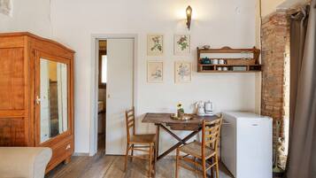 Una cocina compacta con una mesa de madera, sillas, un refrigerador y un armario.