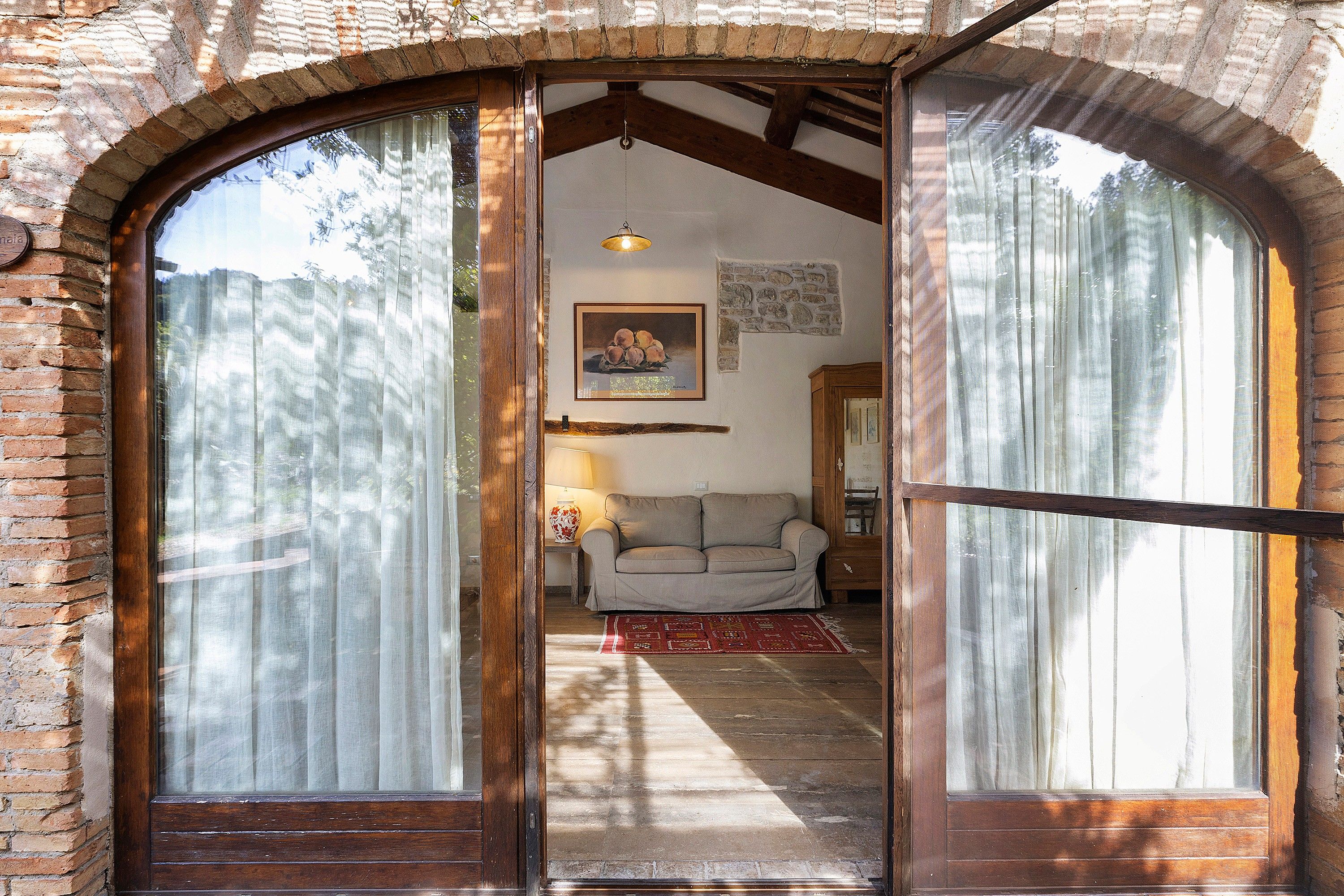 A wooden-framed doorway leading to a living room with a sofa, a lamp, and a painting on the wall.
