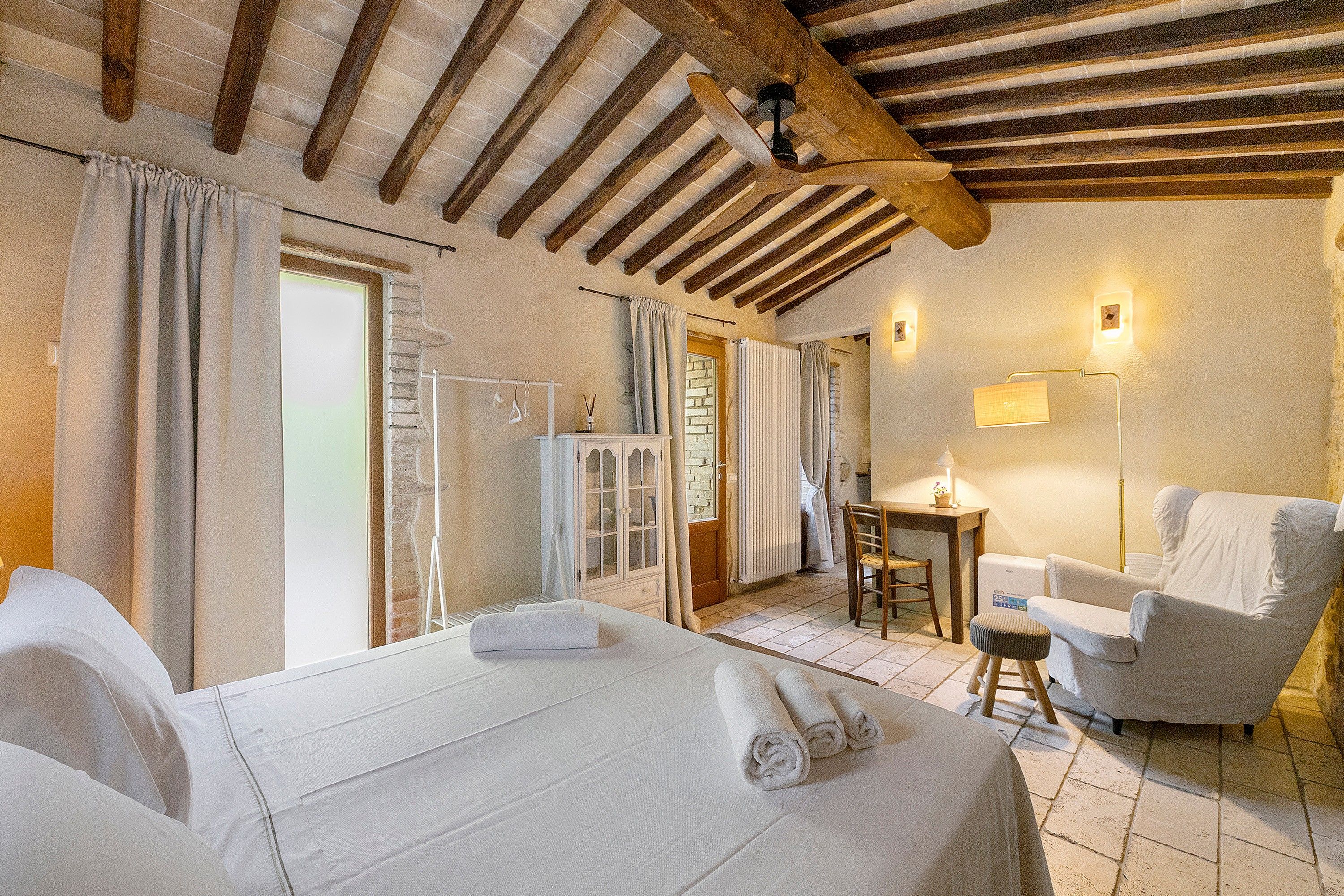 Una camera d'albergo con un letto, una sedia, una scrivania e una lampada.